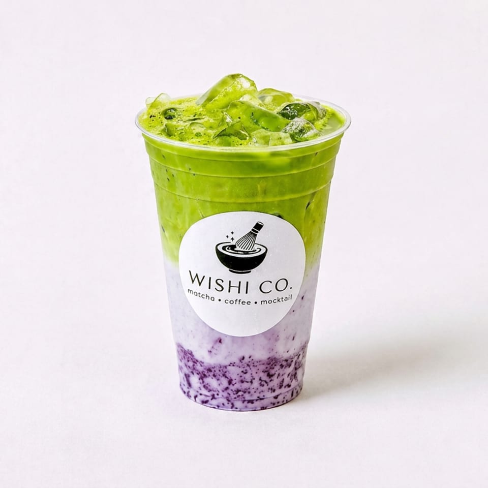 Layered iced matcha drink with purple berry cream in a clear Wishi Co. cup against a white background.